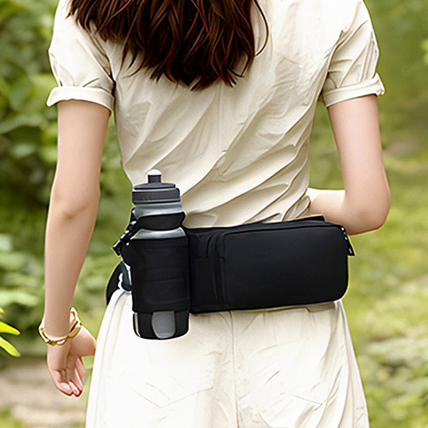 Woman wearing a black waterproof waist bag with a water bottle holder in a natural setting.